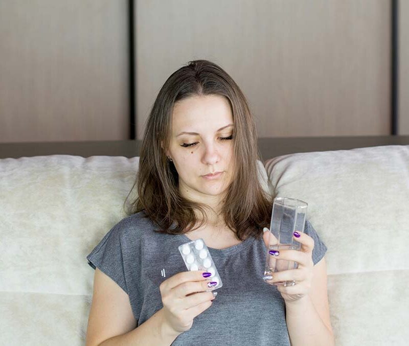 A woman looking at an aspiring with a glass of water