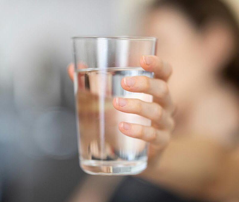 A hand holding a glass filled with water