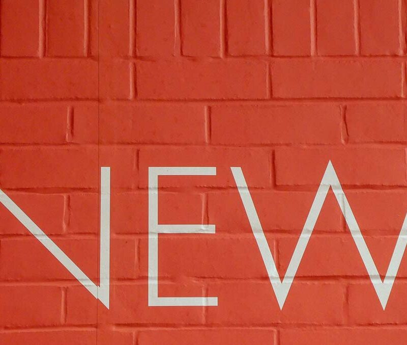 An orange brick wall with the word NEW on it.