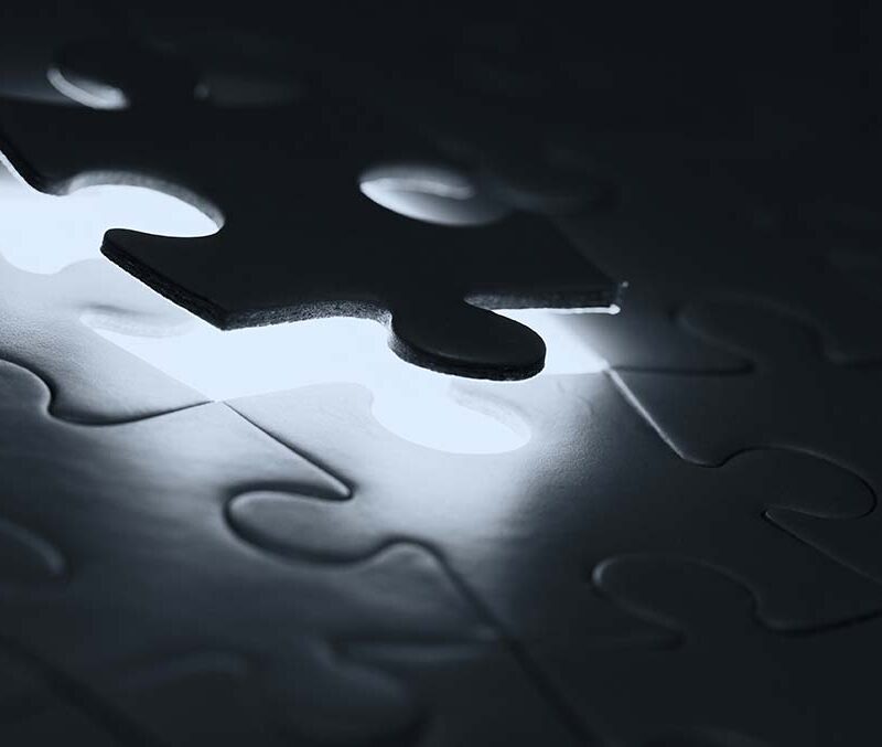 A black and white image of puzzle pieces being assembled.